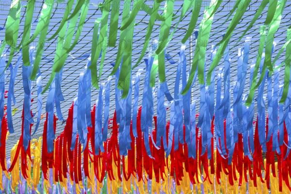 Close up shot of decorative multicolor ribbons waving in the wind at city street holiday, festival