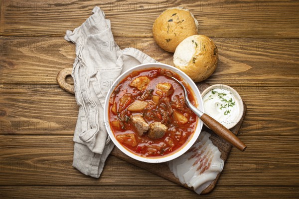 Ukrainian Borscht, red beetroot soup with meat, in white bowl with sour cream, garlic buns