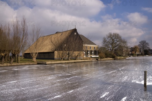 Frozen river the Graafstroom with on the other side a monumental farm in the South Holland village