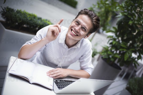 Happy handsome businessman mixes his break and job outdoors, businessman with headphones write some