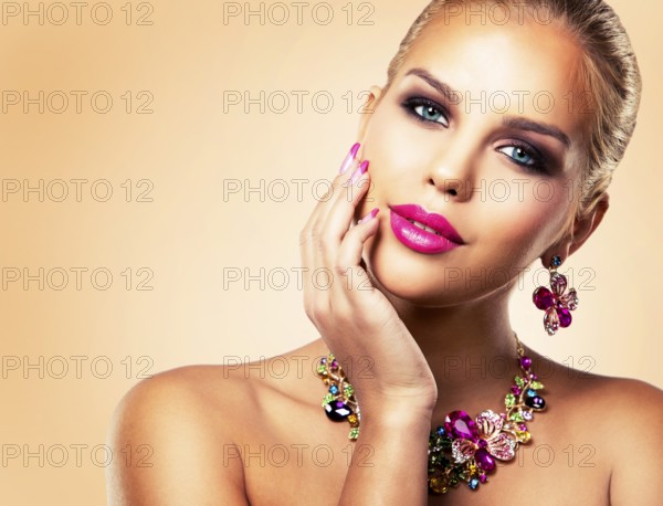 Beautiful woman with dark makeup and pink lipstick posing on beige background wearing flower spring