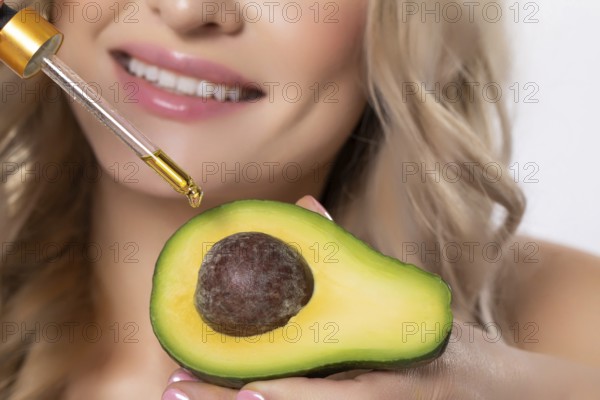 A woman skillfully uses avocado in her skincare routine with a dropper, highlighting beauty and