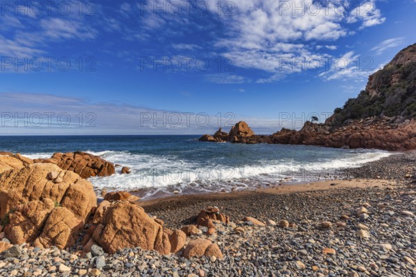 Coastal landscape with red rocks and surf in blue sky and sunshine, Spiaggia di Cala E'Luas,