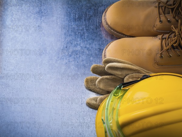 Protective leather gloves waterproof safety boots hard hat and plastic glasses on scratched