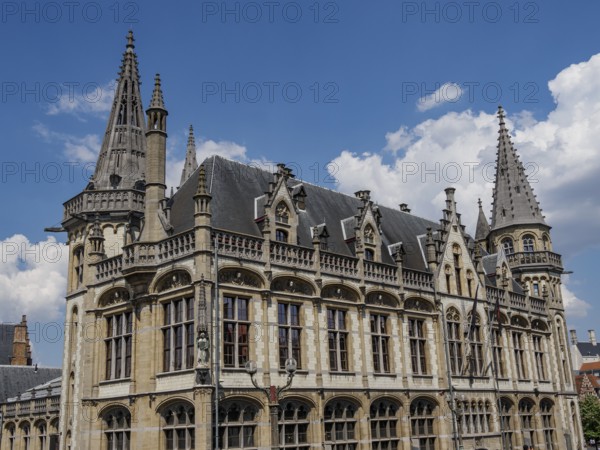Majestic building with pewter towers and detailed decorations on a clear blue sky, Ghent, Belgium,