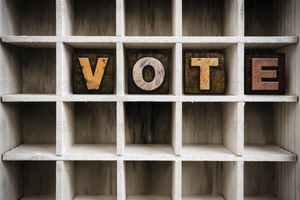 The word VOTE written in vintage ink stained wooden letterpress type in a partitioned printer's