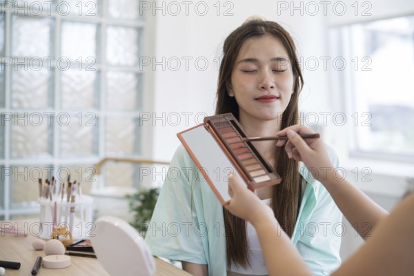 Makeup artist. Professional makeup artist working with beautiful young asian woman applying
