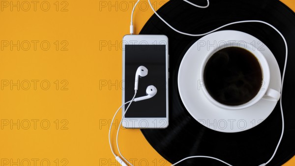 Cup of black coffee on vynil record. Copy space. Listening to music. Retro style. Podcast. Mobile
