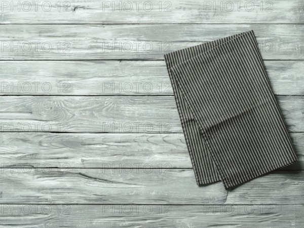 Gray wooden table with balck and white dark linen kitchen towel or textile napkin flat lay. Dark
