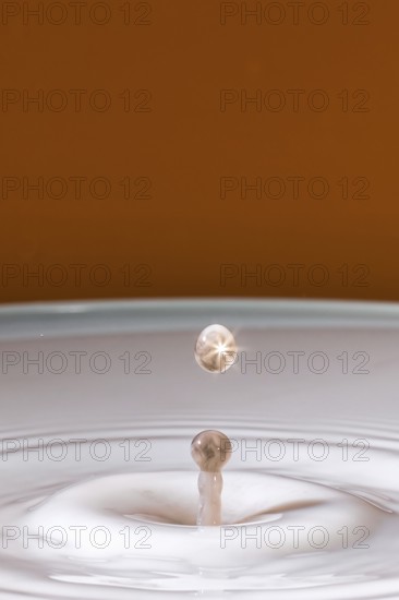 A sparkling drop hits the surface of the milk and creates gentle waves, water droplets, collision,