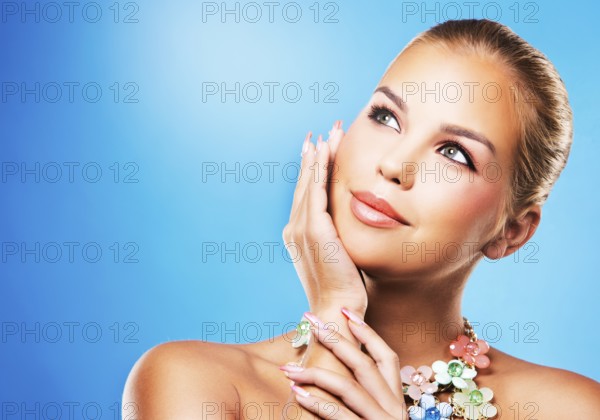 Beautiful woman with dark makeup and pink lipstick posing on blue background wearing flower spring
