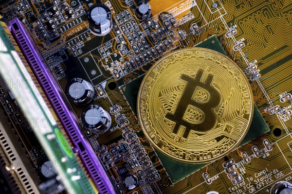 Virtual cryptocurrency money Bitcoin golden coin on a computer printed circuit board PCB. The