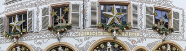 Panoramic photo of a shop front decorated for Christmas with many Father Christmases in golden