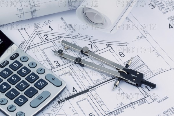 An architect's construction plan with a calculator. Symbolic photo for financing and planning a new