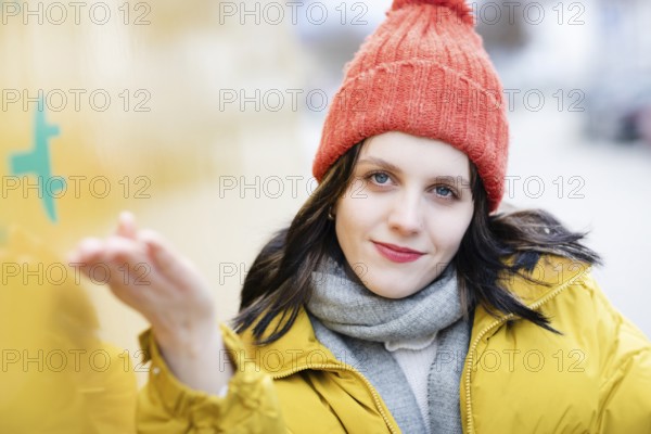 Woman with red hat and yellow jacket points with hand to large electric car for transport, electric