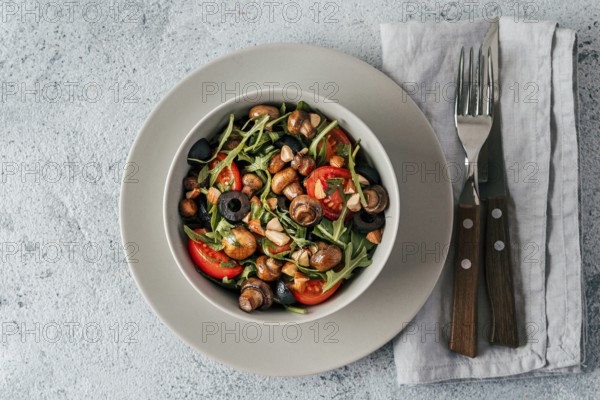 Salad with arugula, mini champignons, cherry tomatoes, black olives, pine nuts. Vegetarian salad