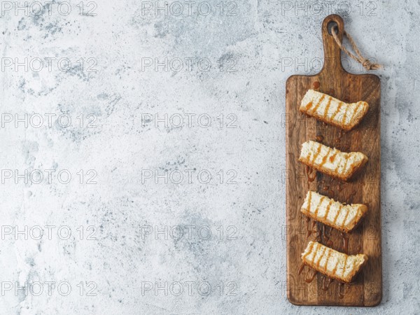 Caramelized cheesecake slices on wooden cuttingboard. Cheesecake on gray cement background with