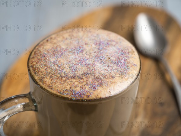 Trendy Coffee with edible glitter. Cup of sparkly coffee or diamond cappuccino on gray table. Copy