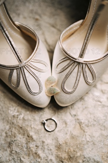Women's earrings in the shape of leaves on the toes of the bride's white shoes with an engagement