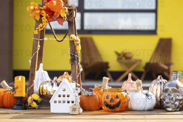 Autumn decor on porch of yellow house outside of pumpkin, lantern, garlands and figure of home and