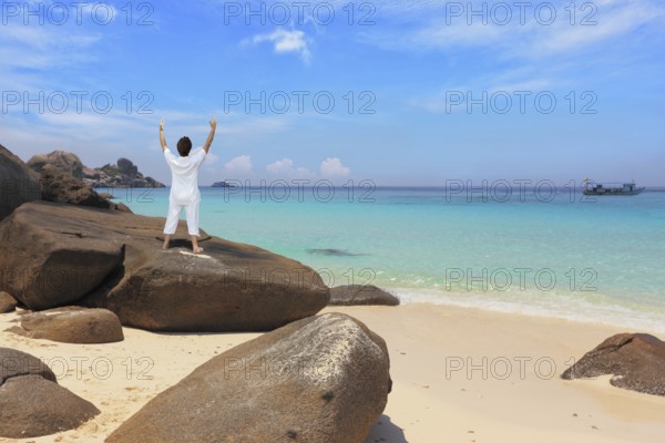 Middle-aged woman dressed in white doing yoga. Asana Blessing of the Sun. Thailand. Gorgeous beach