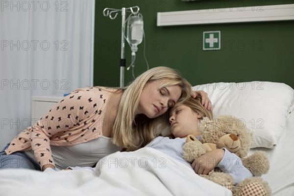 A loving mother gently comforts her sick child, who is lying in a hospital bed, creating a truly