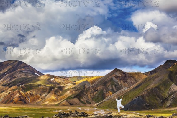 The elderly woman carries out pose of Tree in yoga among thermal sources. The picturesque valley in