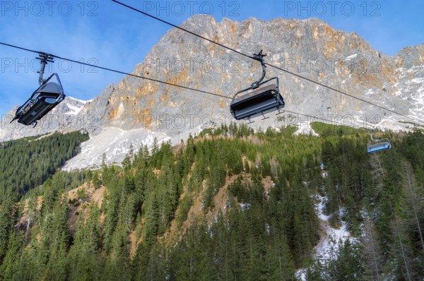 Alpine scenery with the rocky peaks of the Alps mountains and ski lifts rolling on a cableway over