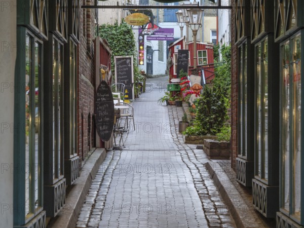 Narrow cobbled alley with old buildings and alleyway café in a cosy atmosphere, Flensburg,