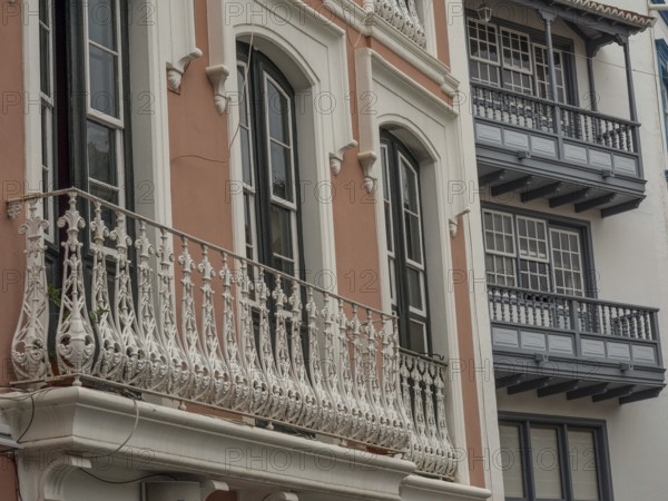 Detailed view of an old building façade with ornate balconies and windows. The colours are muted,