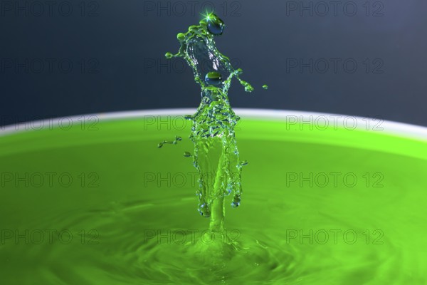 A powerful splash of green liquid with eye-catching water sculptures, water droplets, collision,
