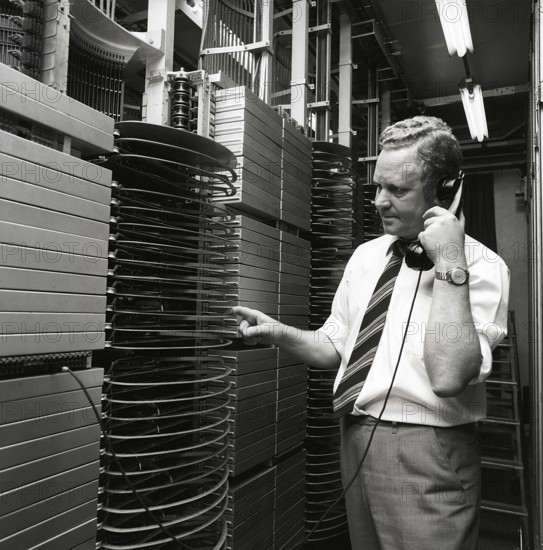 Telephony in the 1970s. A man in a room with an automatic switchboard connecting the calls through