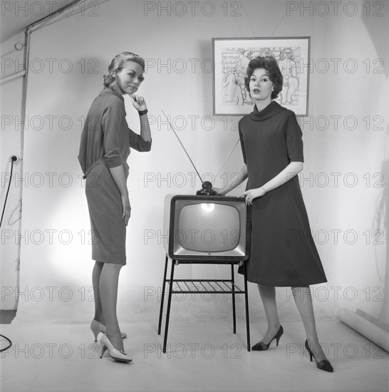 Television in the 1950s. Two young women are standing dressed in a typical 50s dress beside a