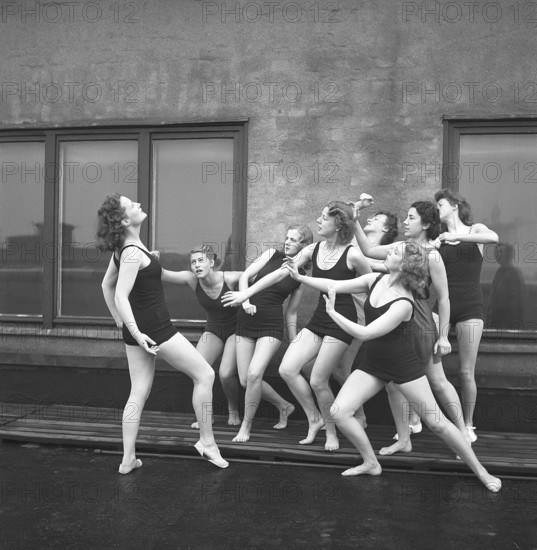 Gymnasts in the 1940s. A group of women gymnasts are training together on a top of a building.
