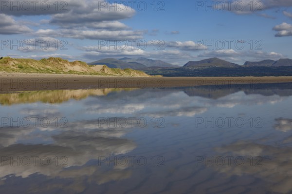 Reflection of clouds and mountains of Snowdonia National Park in the water on the beach,