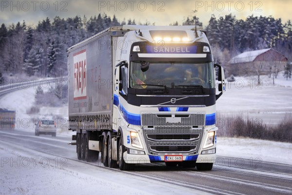 Blue white Volvo FH semi trailer truck Kuljetusliike Harri Sandell Oy with bright headlights on