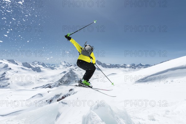 A skier in full sports equipment jumps into the abyss from the top of the glacier against the