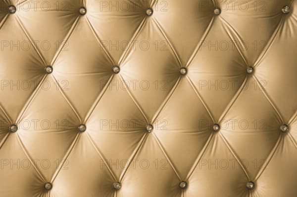 Beige soft textile background with symmetrical buttons on the corners of diamonds. Soft and