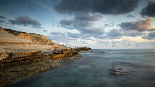 Rocky seashore seascape with wavy ocean and dramatic and beautiful sunset at sea caves coastal area