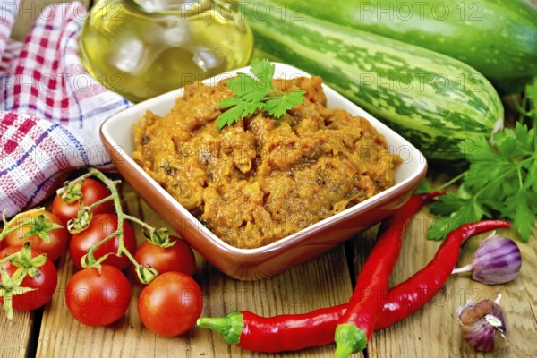 Caviar squash in a clay bowl, tomatoes, red pepper, zucchini, napkin, garlic, vegetable oil on a