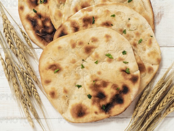 Fresh naan bread on white wooden background with copy space. Top view of several perfect naan