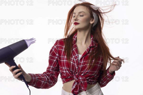A fashionable woman enjoys drying her hair with a blow dryer, capturing a moment of style and
