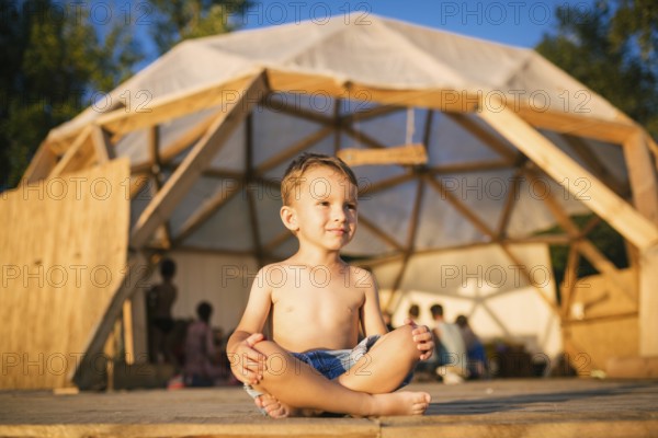 Theme is yoga and children. Caucasian Boy child sitting barefoot cross-legged in lotus position on