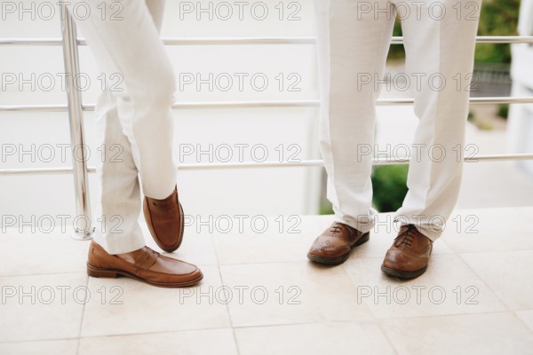 The legs of two men standing on the balcony, close-up. The groom and his best man during the