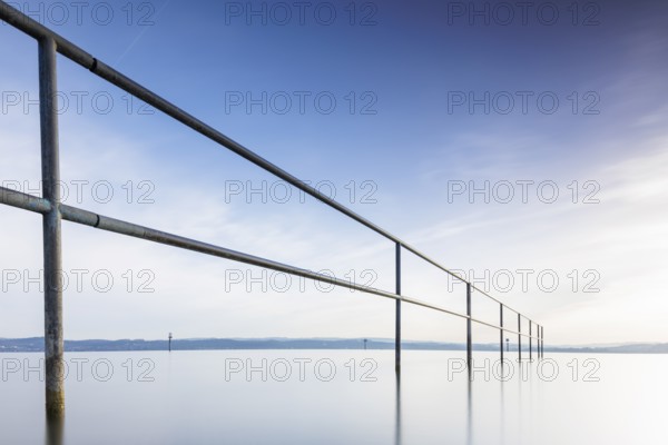 A railing in front of a calm, blue sky and lake, lido, Litzelstetten, Lake Constance,
