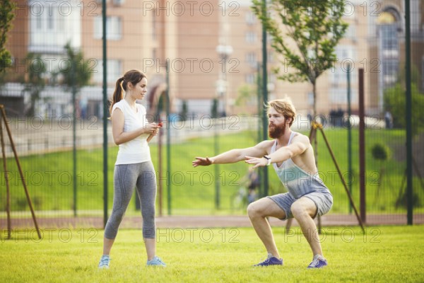 Team work in sports. female trainer training man with beard in park on green grass, lawn at sunset.