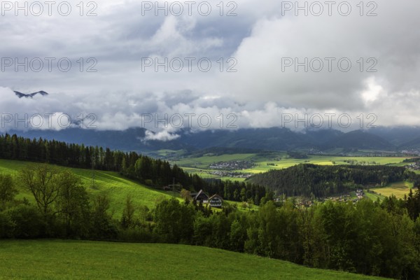 Meadow, farmland and forest area, fog in the background over Reiting massif, view from the lowland,
