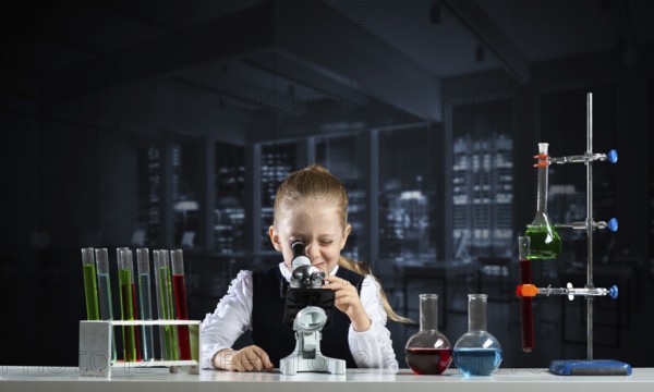 Little girl scientist looking through microscope in classroom at chemistry lesson. School chemical