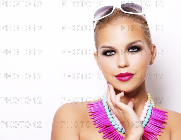 Beautiful woman with dark makeup and pink lipstick posing on white background wearing bright
