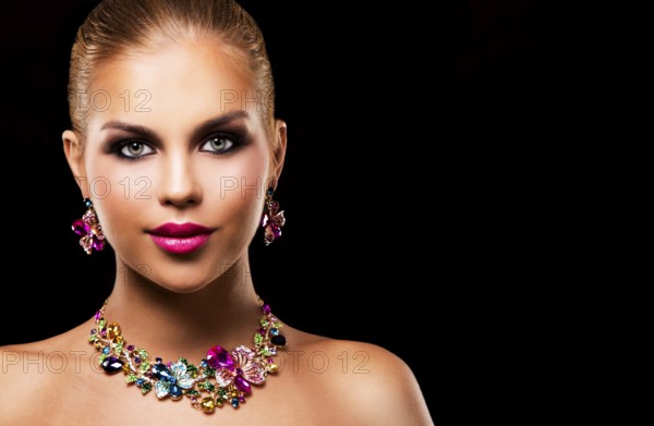 Beautiful woman with dark makeup and pink lipstick posing on black background wearing flower spring